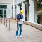 Recém-formado em engenharia civil analisando um projeto no canteiro de obras